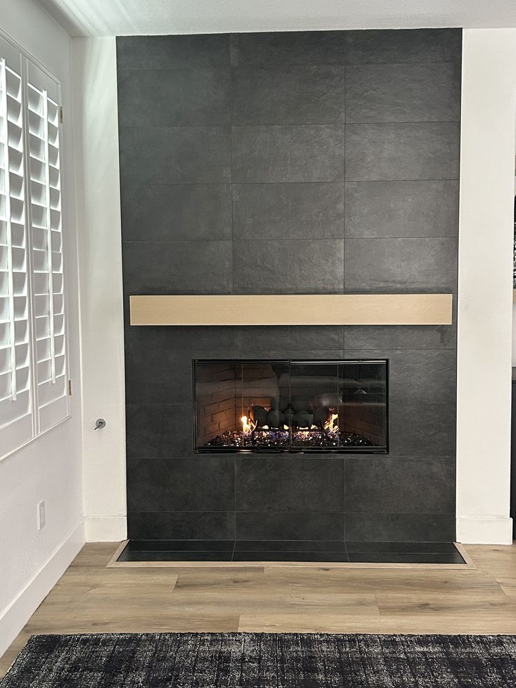 Floor-to-ceiling tile fireplace with wood mantel